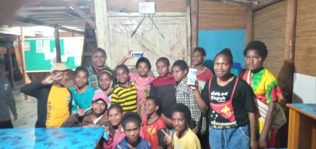 Girls at the YPPK Francis Asisi Moanemani Middle School Dormitory posing in front of the transmitter box in the background. The gadgets in their hands came from other donors. Photo: Sudrijanto SJ